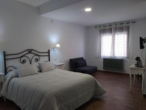 ein Schlafzimmer mit einem großen Bett und einem Stuhl in der Unterkunft Casa Pedro Páez in Belmonte