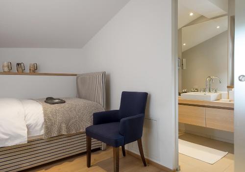 a bedroom with a bed and a blue chair and a sink at Thurnher's Residences in Zürs am Arlberg