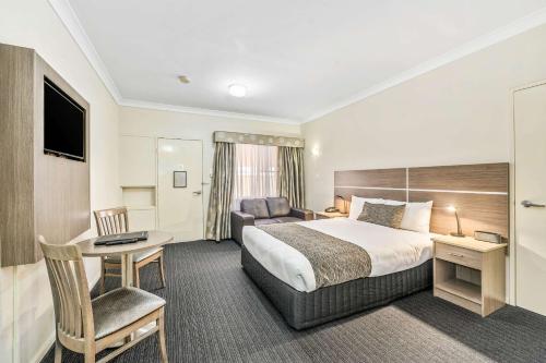a hotel room with a bed and a desk and a couch at Quality Inn Ashby House Tamworth in Tamworth