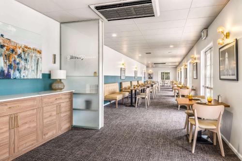 a dining room with a row of tables and chairs at Quality Inn Ashby House Tamworth in Tamworth