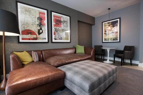 a living room with a brown leather couch and a table at Malmaison Birmingham in Birmingham