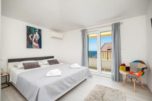 Habitación blanca con cama, silla y ventana en Mare, en Makarska