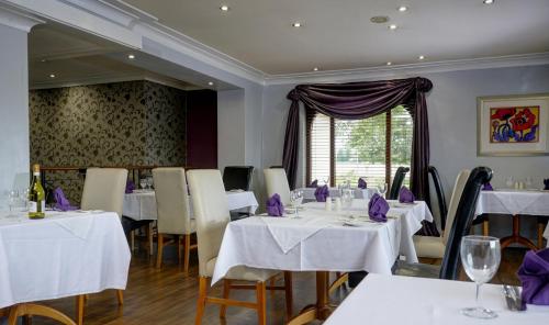 un restaurante con mesas y sillas blancas y una ventana en Widnes Halton Everglades Park Hotel, en Widnes