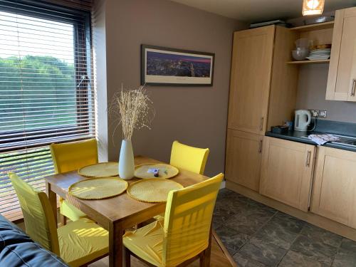 a dining room table with yellow chairs and a kitchen at Millennium Apartments in Newcastle upon Tyne