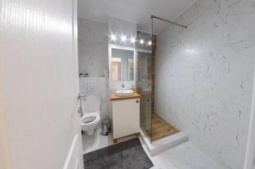 a white bathroom with a toilet and a sink at Studio with a view in city center in Târgovişte