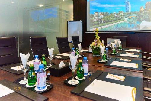 Rose Park Hotel - Al Barsha, Opposite Metro Station في دبي: قاعة المؤتمرات مع طاولة طويلة مع زجاجات عليها