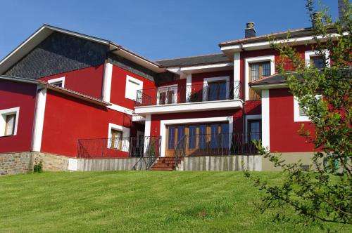 a red building with a yard in front of it at Hotel Rural Suquin in Navia