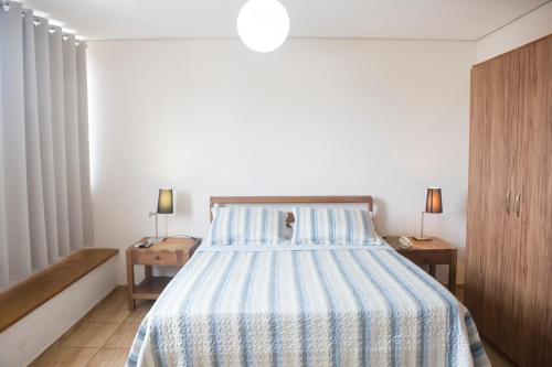 a bedroom with a bed with a blue and white striped bedspread at Grand Enio Hotel e Cantina in Varginha