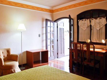 um quarto com uma cama, uma secretária e uma cadeira em Hotel Dom Otto em Vespasiano