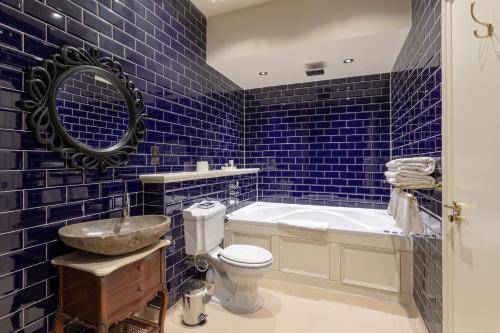 a blue tiled bathroom with a toilet and a sink at The Coal Exchange Hotel in Cardiff