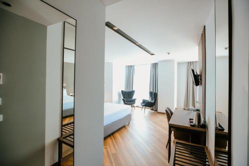 1 dormitorio con cama, escritorio y espejo en Klajdi Resort & SPA, en Golem