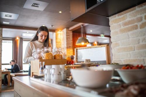 une femme debout dans une cuisine préparant de la nourriture dans l'établissement Le Hameau du Kashmir, à Val Thorens