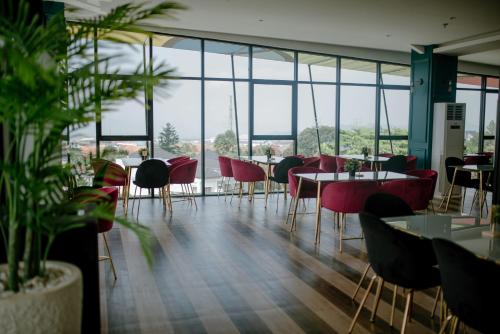 un restaurant avec des tables, des chaises et des fenêtres dans l'établissement The Bountie Hotel and Convention Centre Sukabumi, à Sukabumi