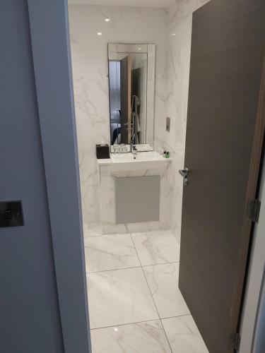 a white bathroom with a sink and a mirror at Dean Park Hotel in Kirkcaldy