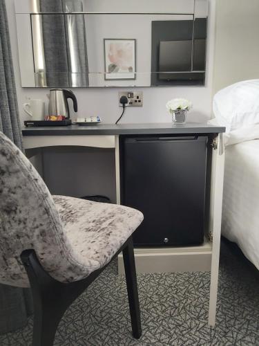 a desk with a chair and a television in a hotel room at Dean Park Hotel in Kirkcaldy