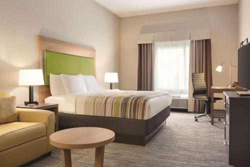 Country Inn & Suites by Radisson, Greensboro, NC في جرينسبورو: غرفة في الفندق بسرير وكرسي ومكتب