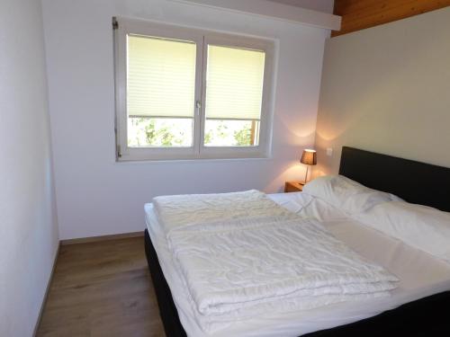 a white bed in a bedroom with a window at Residence Edelweiss C331 in Bellwald