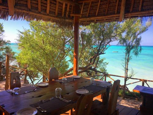 a wooden table with a view of the ocean at The Island - Pongwe Lodge in Pongwe