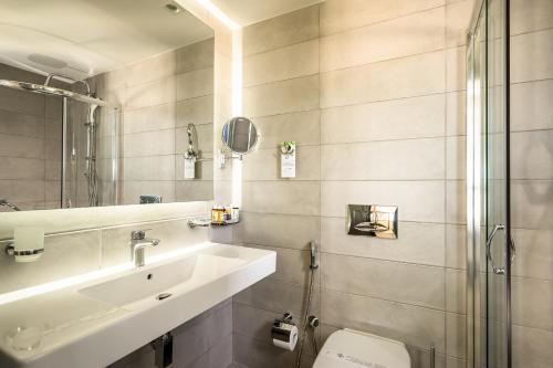 a bathroom with a sink and a toilet and a mirror at Porto Galini Seaside Resort & Spa in Nikiana