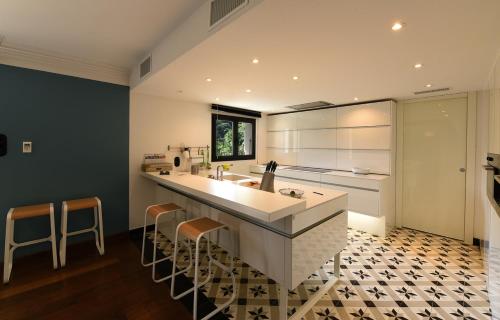 une cuisine avec un grand comptoir blanc et des tabourets dans l'établissement Appart'hotel Fior Di Ribba, à Sartène