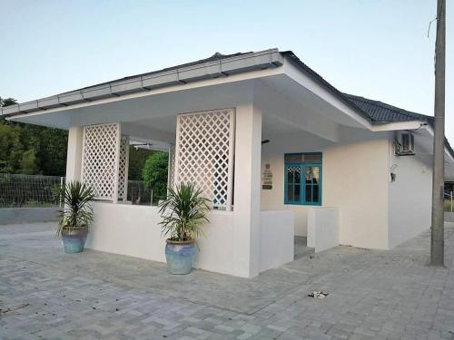 a white house with two potted plants in front of it at Ulu Rhu Villa in Tanjung Rhu 