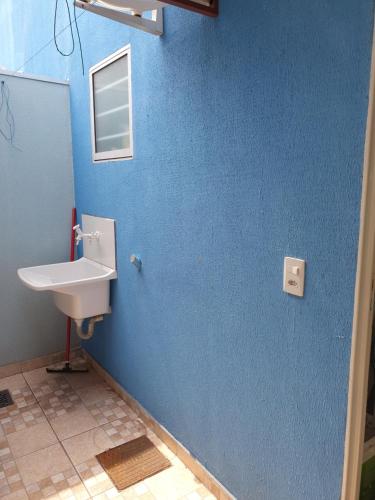 a bathroom with a sink and a blue wall at Kitnet Camiloca in Campo Grande