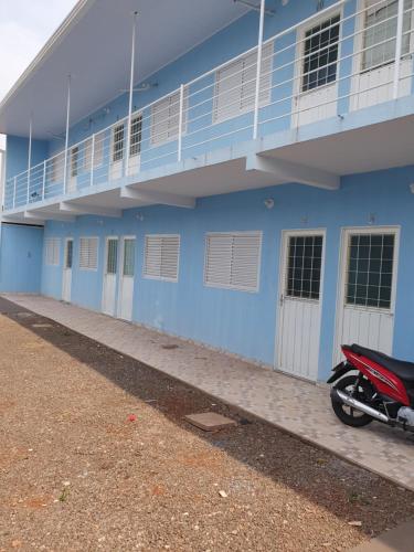 a motorcycle parked in front of a blue building at Kitnet Camiloca in Campo Grande