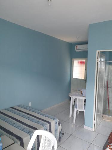 a blue room with a bed and a table at Kitnet Camiloca in Campo Grande