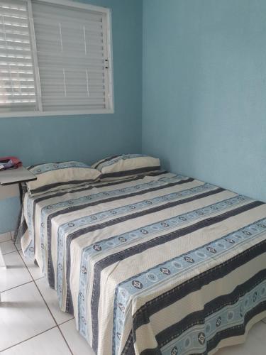 a bed in a bedroom with a blue wall at Kitnet Camiloca in Campo Grande