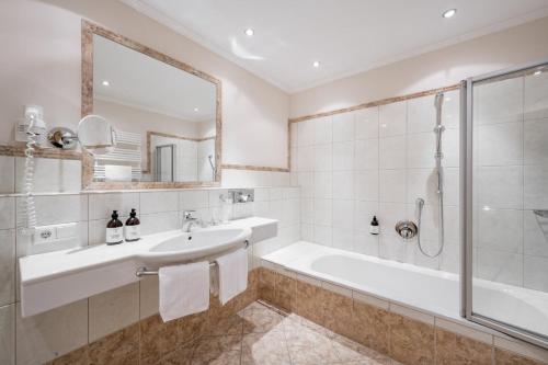 a bathroom with a tub and a sink and a shower at SKI - GOLF - WELLNESS Hotel Riml in Hochgurgl