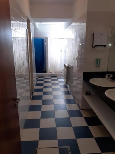 a bathroom with a checkered floor and two sinks at Stone Farm Hostel in Felgueiras