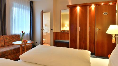 a hotel room with a bed and a couch at Hotel Ilbertz Garni in Cologne