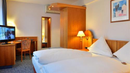 een hotelkamer met 2 bedden en een televisie bij Hotel Ilbertz Garni in Keulen