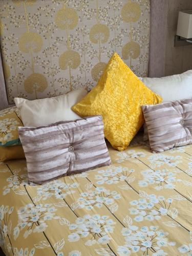 Una cama con dos almohadas y una almohada amarilla. en Mini lodge hot tub hols at Kingfisher Court, en Tattershall