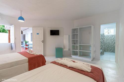 Cette chambre blanche comprend deux lits et une télévision. dans l'établissement Pousada Angatu Arraial - Rua do mucugê, à Arraial d'Ajuda