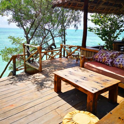 a wooden deck with a couch and a coffee table at The Island - Pongwe Lodge in Pongwe