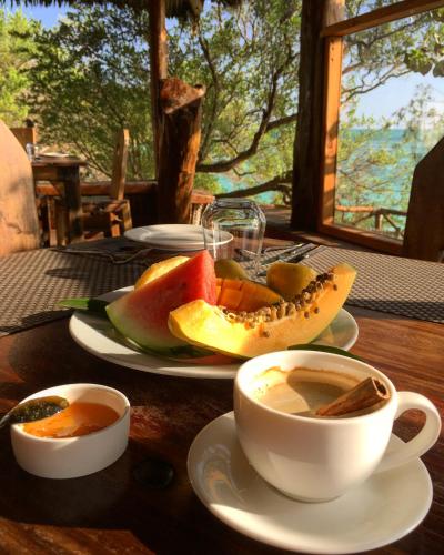 a table with plates of fruit and cups of coffee at The Island - Pongwe Lodge in Pongwe