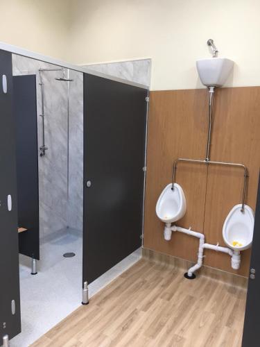 a bathroom with two urinals and a shower at Shepherds Hut at Wern Mill in New Quay