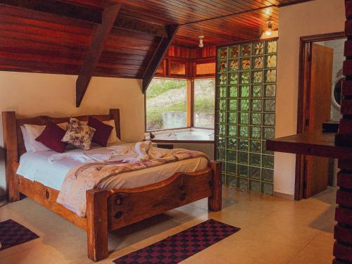 a bedroom with a wooden bed in a room with a window at Pousada Vila Lubia - Chalés Monte Verde in Monte Verde