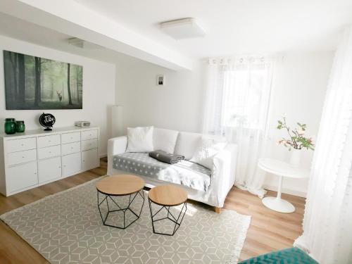 Sala de estar blanca con sofá y 2 mesas en Dream Green Apartment 'Meadow', en Gladenbach