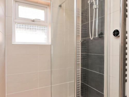 a shower with a glass door and a window at The Willows in Melton Mowbray