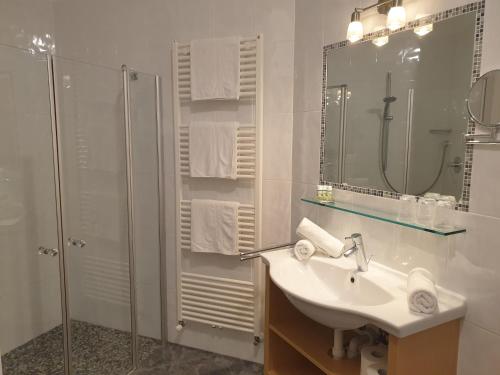 a white bathroom with a sink and a shower at Hotel Garni Herz in Tirolo