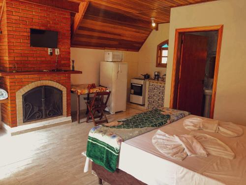 a kitchen with a fireplace and a bed in a room at Pousada Vila Lubia - Chalés Monte Verde in Monte Verde
