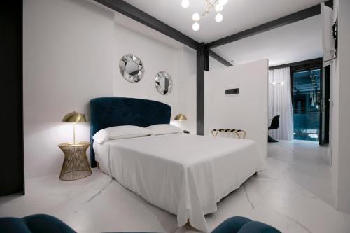 Azzoli Trapani - Apartments&Skypool - Adults Only في تراباني: غرفة نوم بيضاء بسرير وكرسي ازرق