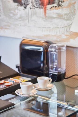 two coffee cups on a table with a coffee maker at Silken Ciudad de Vitoria in Vitoria-Gasteiz