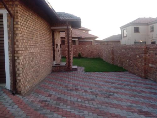 a brick retaining wall with a patio and a yard at Tumi's Home away- 3 Bedroom in Witbank