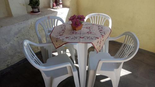 Una mesa blanca con tres sillas y un jarrón de flores. en Pousada Nascentes da Canastra en São João Batista do Glória