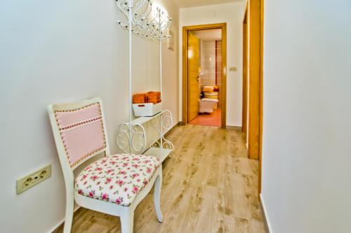 a white chair with a floral seat in a hallway at ISLAND HVAR LUXE Holiday Villa Maslina with Beach in Milna