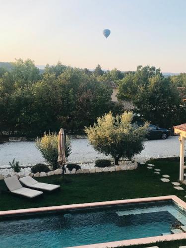 a backyard with a swimming pool with chairs and a dog at villa Luberon in Saint-Saturnin-les-Apt