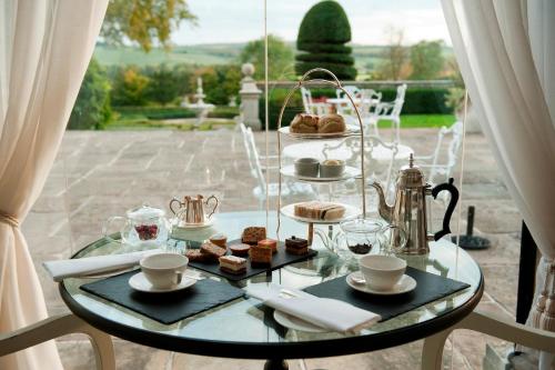 a glass table with a tray of pastries on it at Danesfield House Hotel And Spa in Marlow